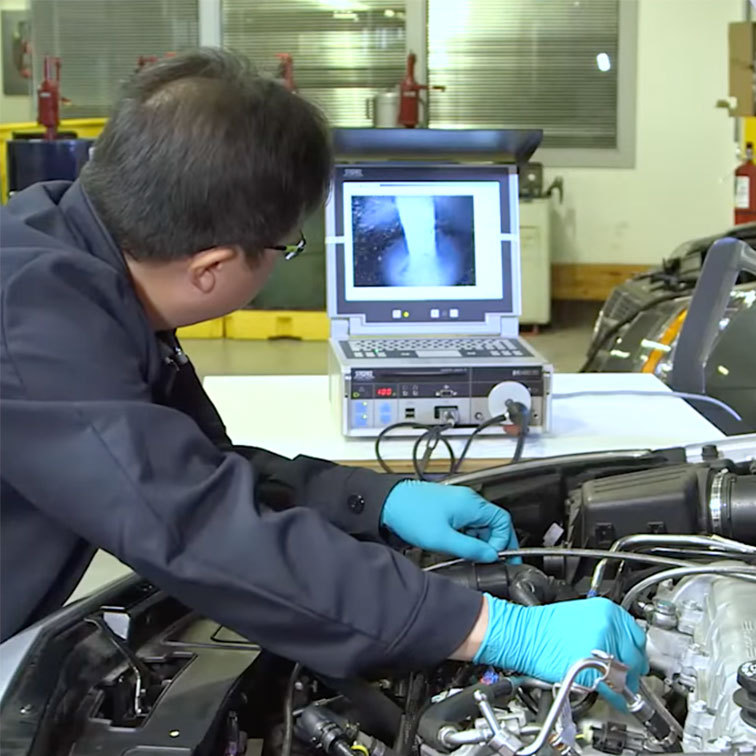 Mechanic using a specialised camera to look inside an engine