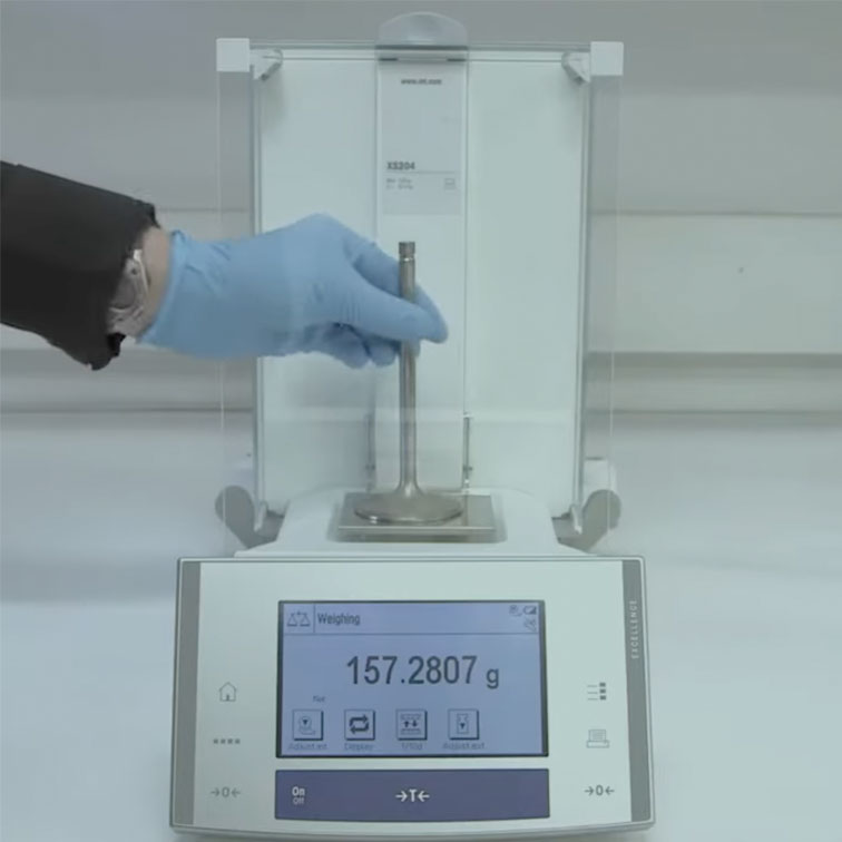 Car engine intake valve being placed on a weighing scale