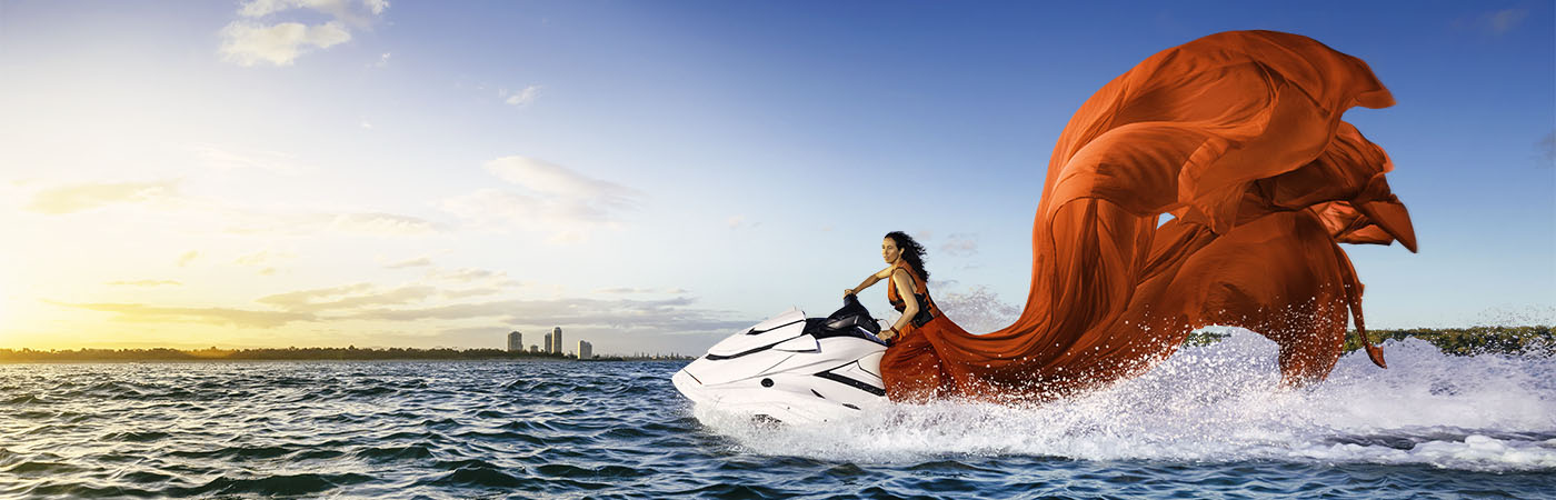 A brown-haired lady in a dazzling red ball gown, riding a jet ski through the gold coast waters, depicts the meaning of Caltex's 'Everyone Deserves the Fancy Stuff' slogan