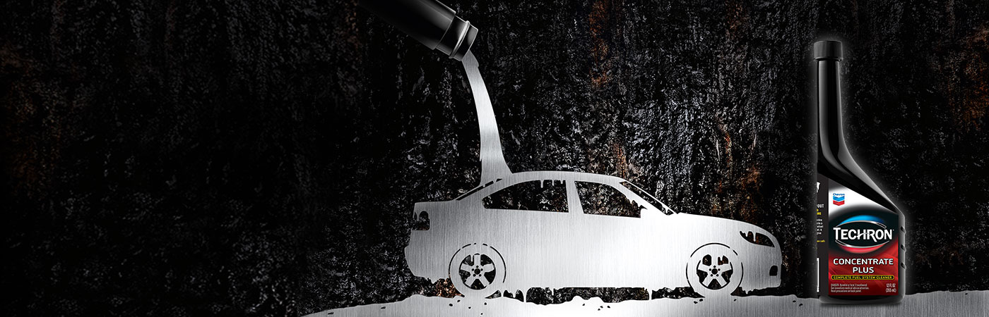 Bottle Techron® D Concentrate with engine pistons and a car driving against an evening cityscape